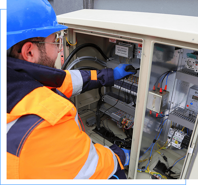 A man in an orange and blue jacket working on a machine.